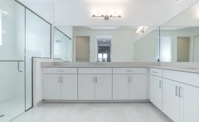 a spacious en suite bathroom with a granite countertop sink and mirror