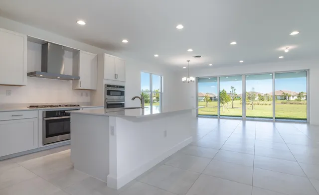 a large kitchen with stainless steel appliances granite countertop a large counter top a stove and a refrigerator with wooden floor