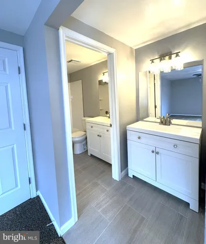a spacious bathroom with a double vanity sink a toilet and a mirror
