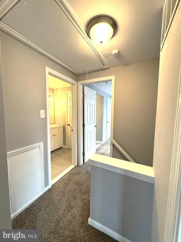 a view of a hallway with wooden floor and a bathroom