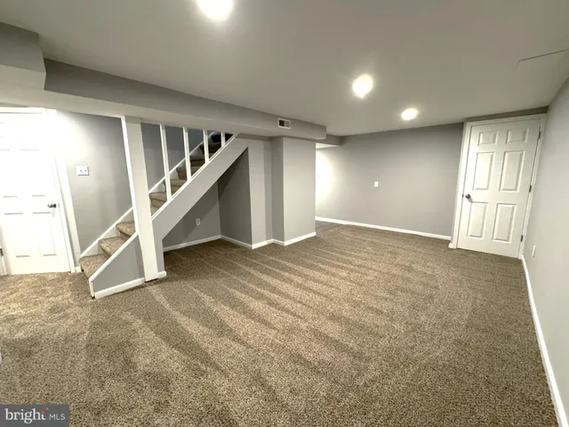 a view of an empty room with stairs and a living room