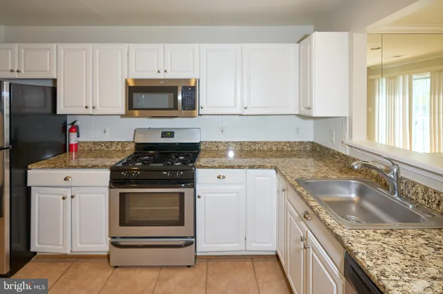 a kitchen with granite countertop a sink stove and cabinets