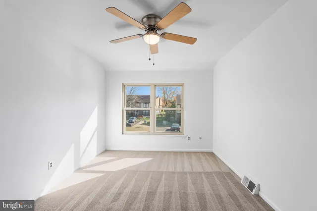 an empty room with a window and a fan