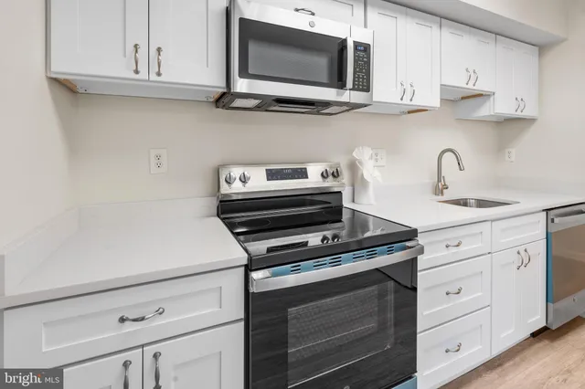a kitchen with stainless steel appliances granite countertop white cabinets a microwave oven a sink and dishwasher