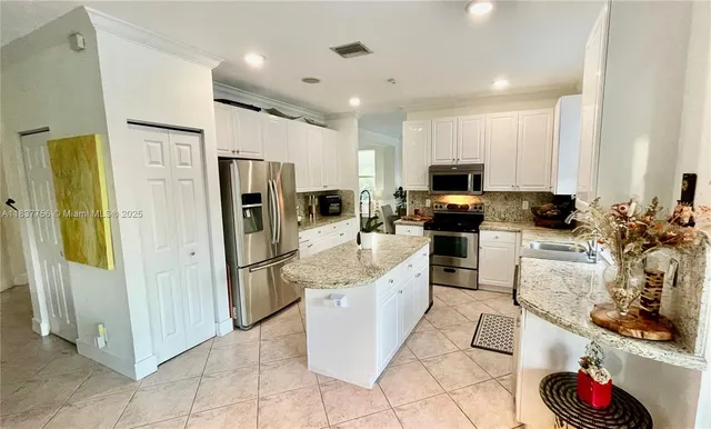 a large kitchen with stainless steel appliances granite countertop a refrigerator and a stove top oven