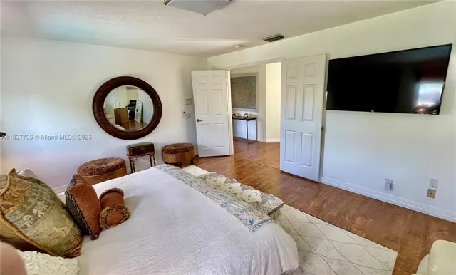 a bedroom with a large bed and a flat tv screen on dresser