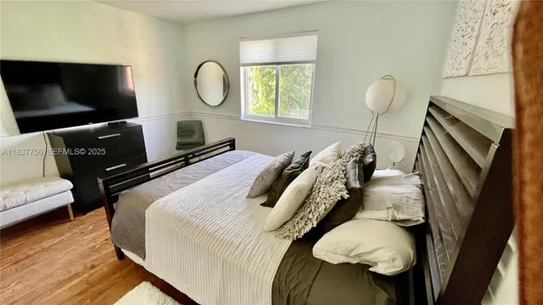a bedroom with bed and a flat tv screen on dresser