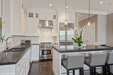a kitchen with stainless steel appliances granite countertop a stove a sink a microwave a refrigerator and white cabinets