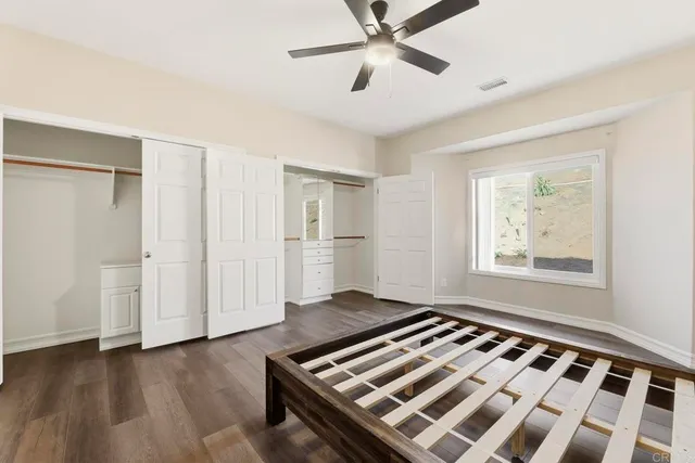 an empty room with wooden floor chandelier fan and windows