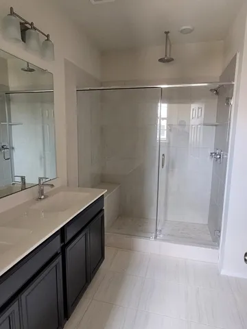 a bathroom with a shower sink vanity and mirror