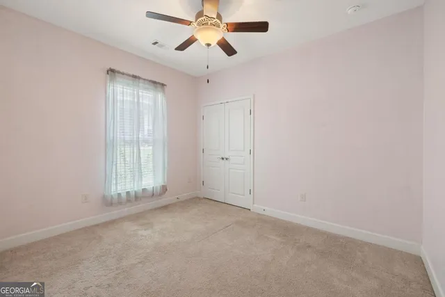 an empty room with a ceiling fan and a window