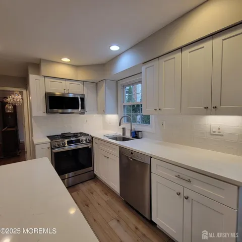 a kitchen with granite countertop white cabinets and stainless steel appliances