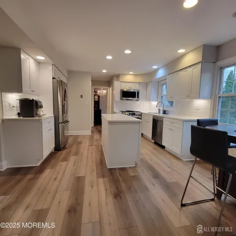 a kitchen with kitchen island white cabinets and stainless steel appliances
