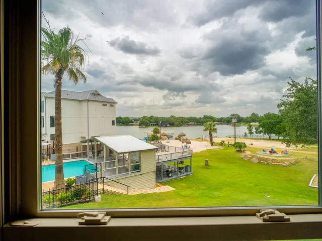 a view of a swimming pool with lawn chairs under an umbrella