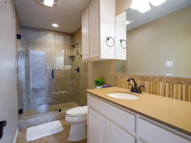 a bathroom with a granite countertop sink a toilet and shower