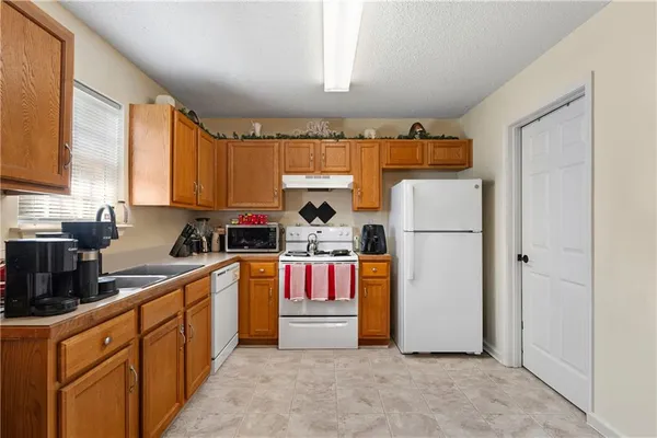 a kitchen with refrigerator a stove top oven a sink and cabinets
