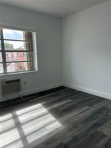 an empty room with wooden floor & closet area