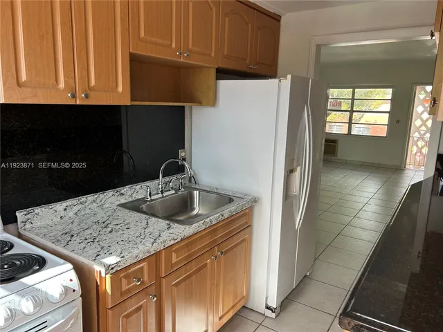 a kitchen with granite countertop a refrigerator and a sink