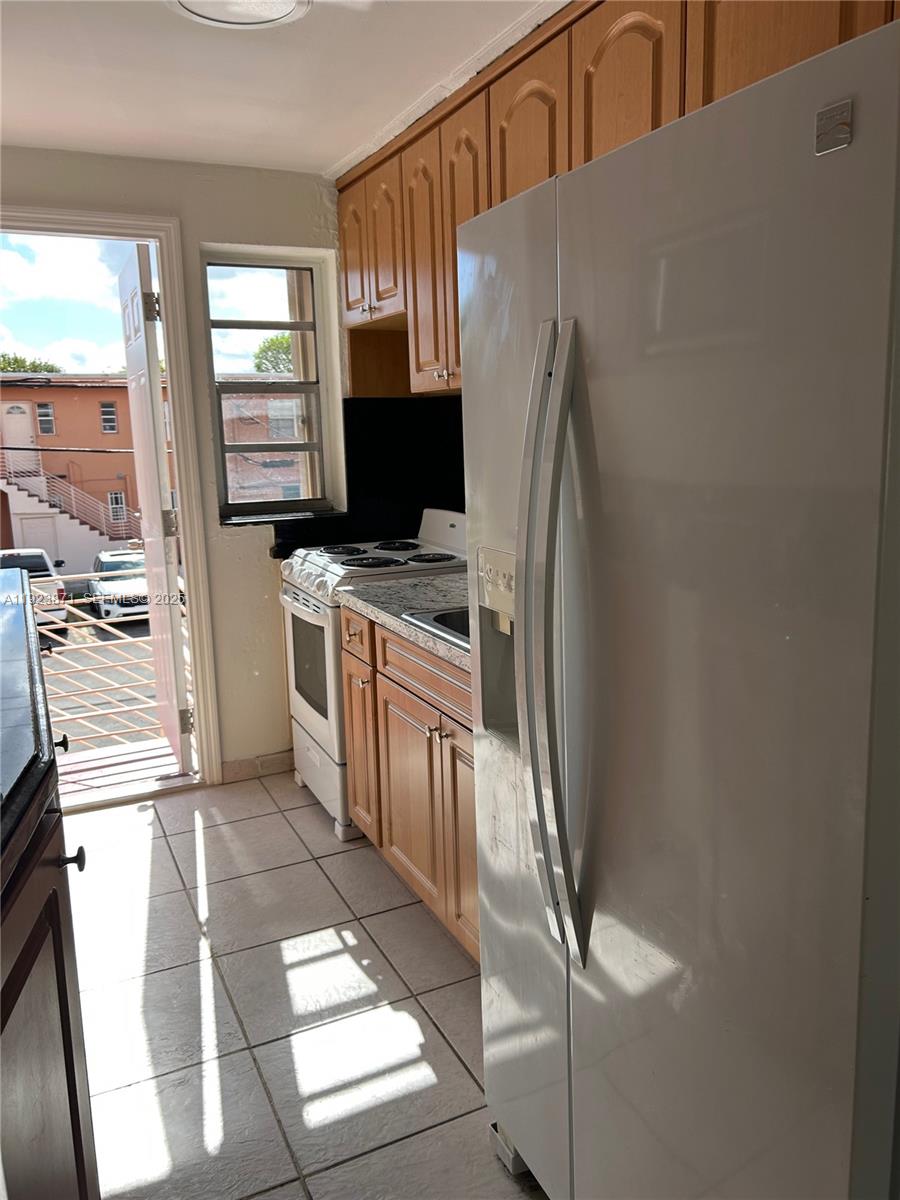 3400 Southwest 9th Terrace, Unit 2B Miami, FL 33135 - Photo 9 of 25 a kitchen with stainless steel appliances granite countertop a refrigerator and a stove top oven