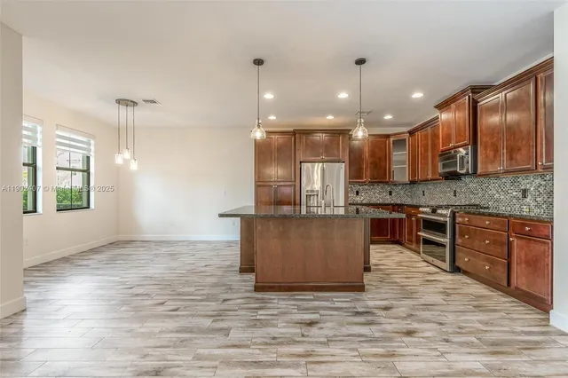 a kitchen with kitchen island granite countertop a stove a sink a refrigerator and a wooden cabinets