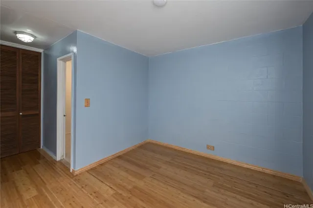 a view of an empty room with wooden floor and closet