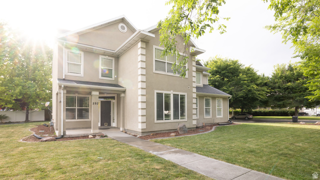 Two-story stucco residence with a covered front porch, prominent window trim, and multiple large windows