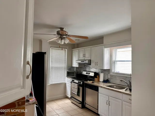 a kitchen with a sink appliances cabinets and a window