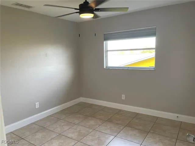 an empty room with a window and ceiling fan