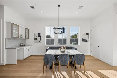 a kitchen with stainless steel appliances kitchen island granite countertop a stove a sink a dining table and chairs with wooden floor
