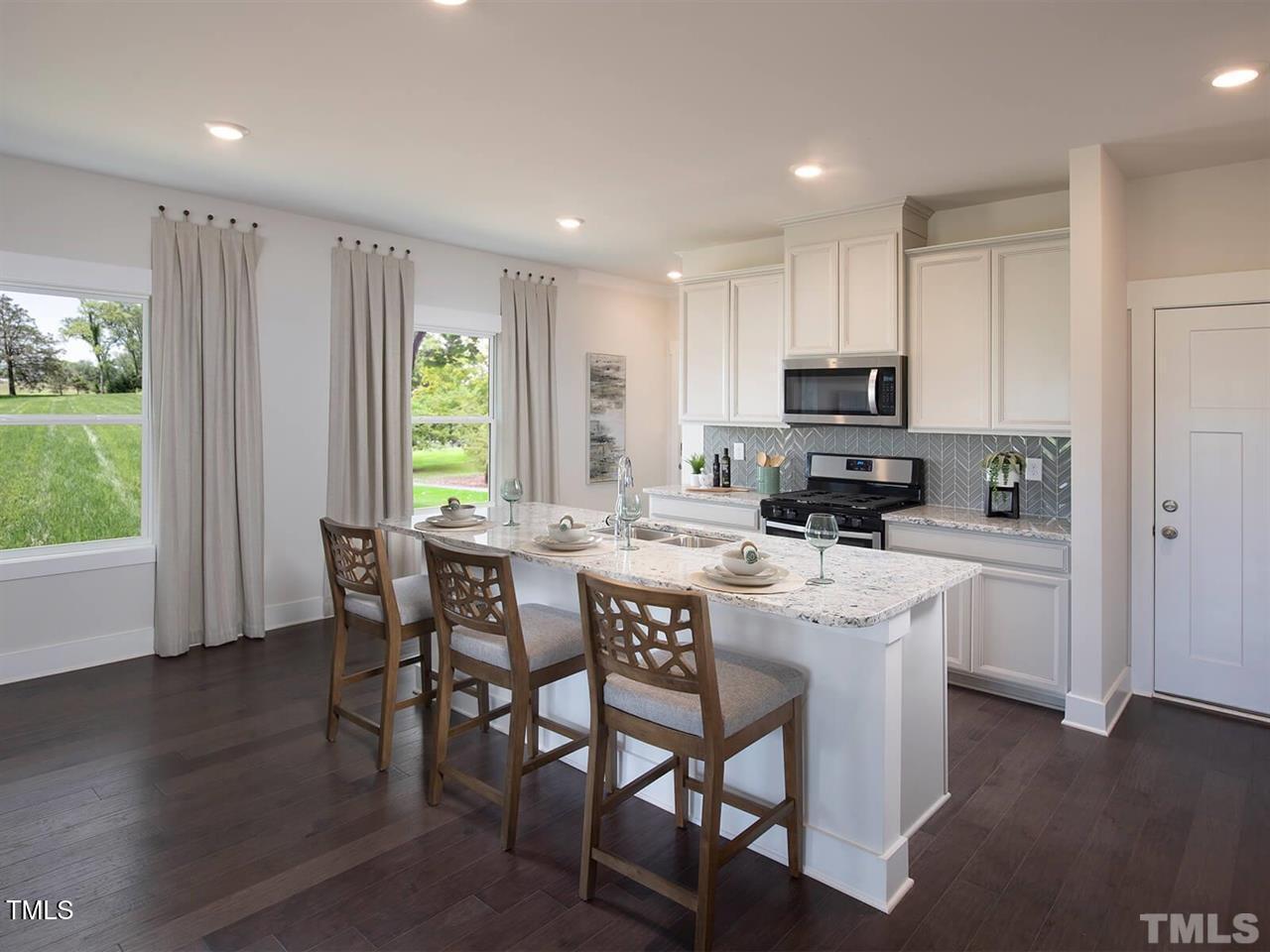 912 Field Ivy Drive Fuquay-Varina, NC 27526 - Photo 23 of 27 a kitchen with kitchen island a dining table chairs and a refrigerator