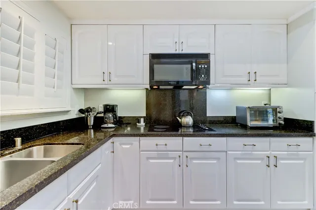 a kitchen with granite countertop white cabinets and a sink