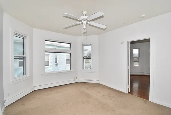 an empty room with windows and ceiling fan