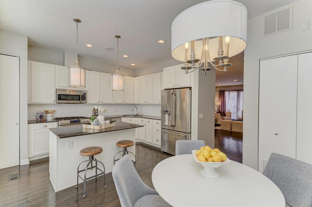 512 North Peoria Street Chicago, IL 60642 - Photo 12 of 32 a kitchen with stainless steel appliances granite countertop a stove a refrigerator a sink a dining table and chairs with wooden floor