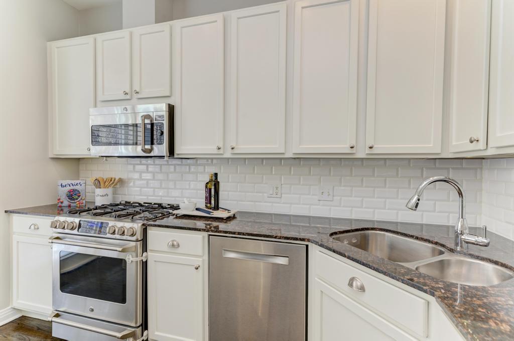 512 North Peoria Street Chicago, IL 60642 - Photo 17 of 32 a kitchen with granite countertop white cabinets sink and stainless steel appliances