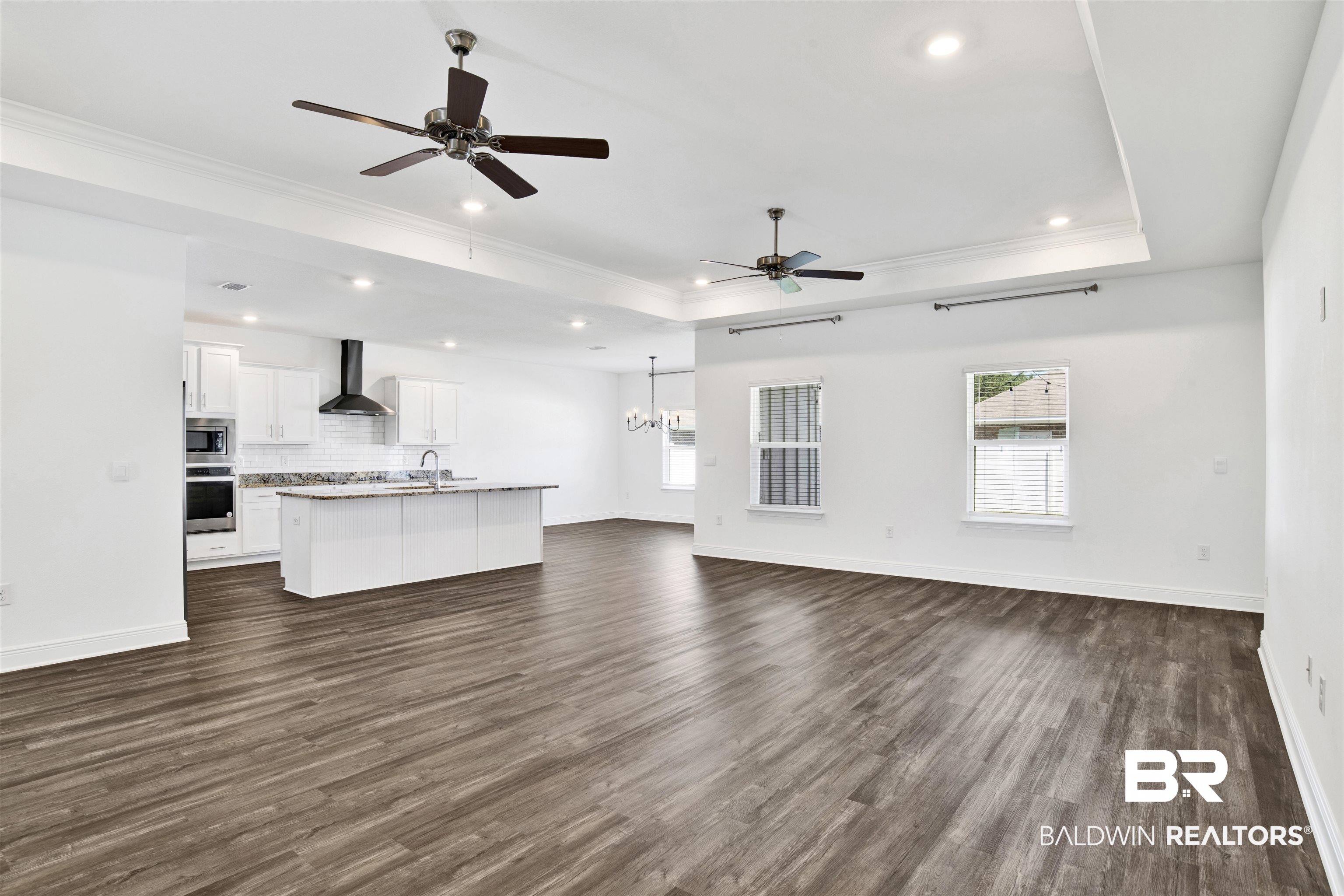 11602 Genuine Risk Circle Daphne, AL 36526 - Photo 7 of 30 Unfurnished living room featuring ceiling fan, dark wood-style flooring, recessed lighting, crown molding, and a raised ceiling