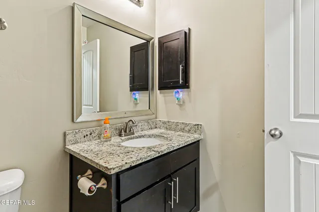 a bathroom with a granite countertop sink and a mirror