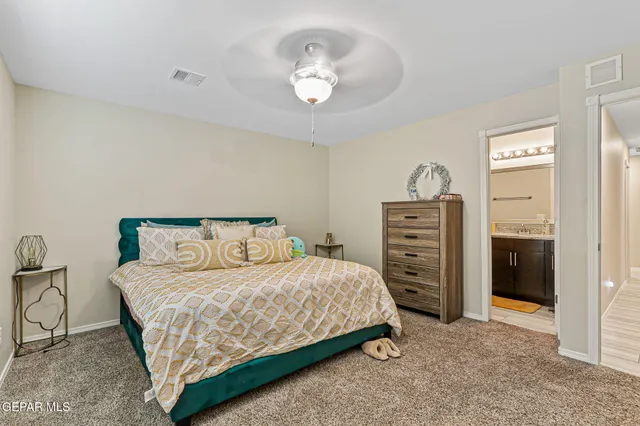 a bedroom with a bed a chandelier and a dresser