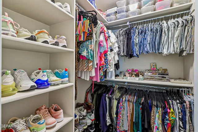 a view of walk in closet with clothes and shoes
