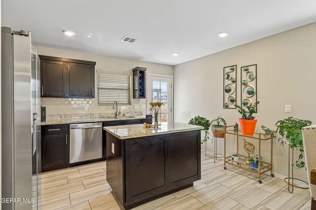 a kitchen with stainless steel appliances granite countertop a sink and a refrigerator