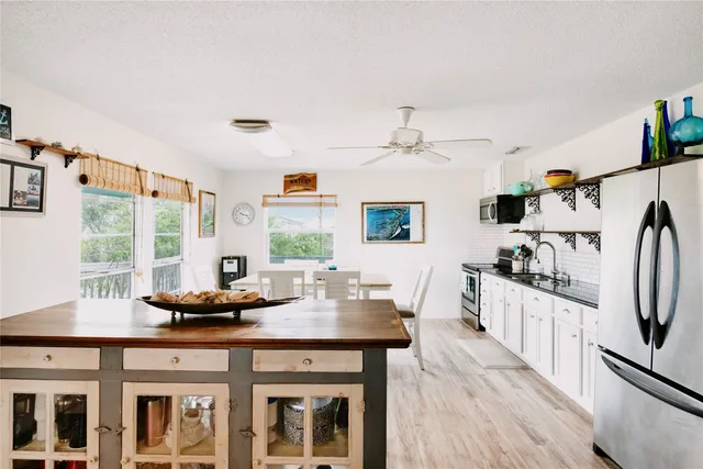 a kitchen with stainless steel appliances wooden floor and large window