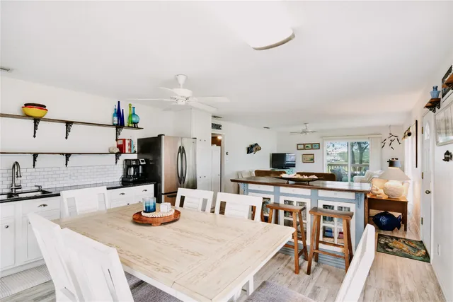 a kitchen with stainless steel appliances kitchen island granite countertop a table chairs and a refrigerator