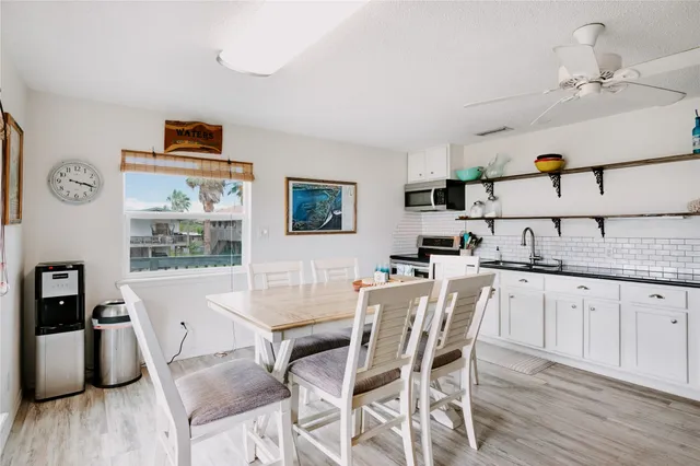 a kitchen with granite countertop a dining table chairs cabinets and wooden floor