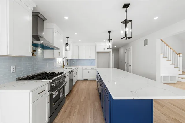 a kitchen with stainless steel appliances a sink a stove a refrigerator and white cabinets