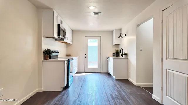 a kitchen with white cabinets and wooden floor