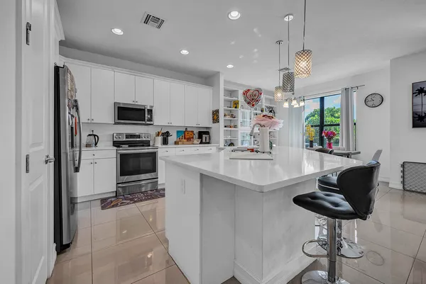 a kitchen with stainless steel appliances kitchen island granite countertop a sink and a refrigerator