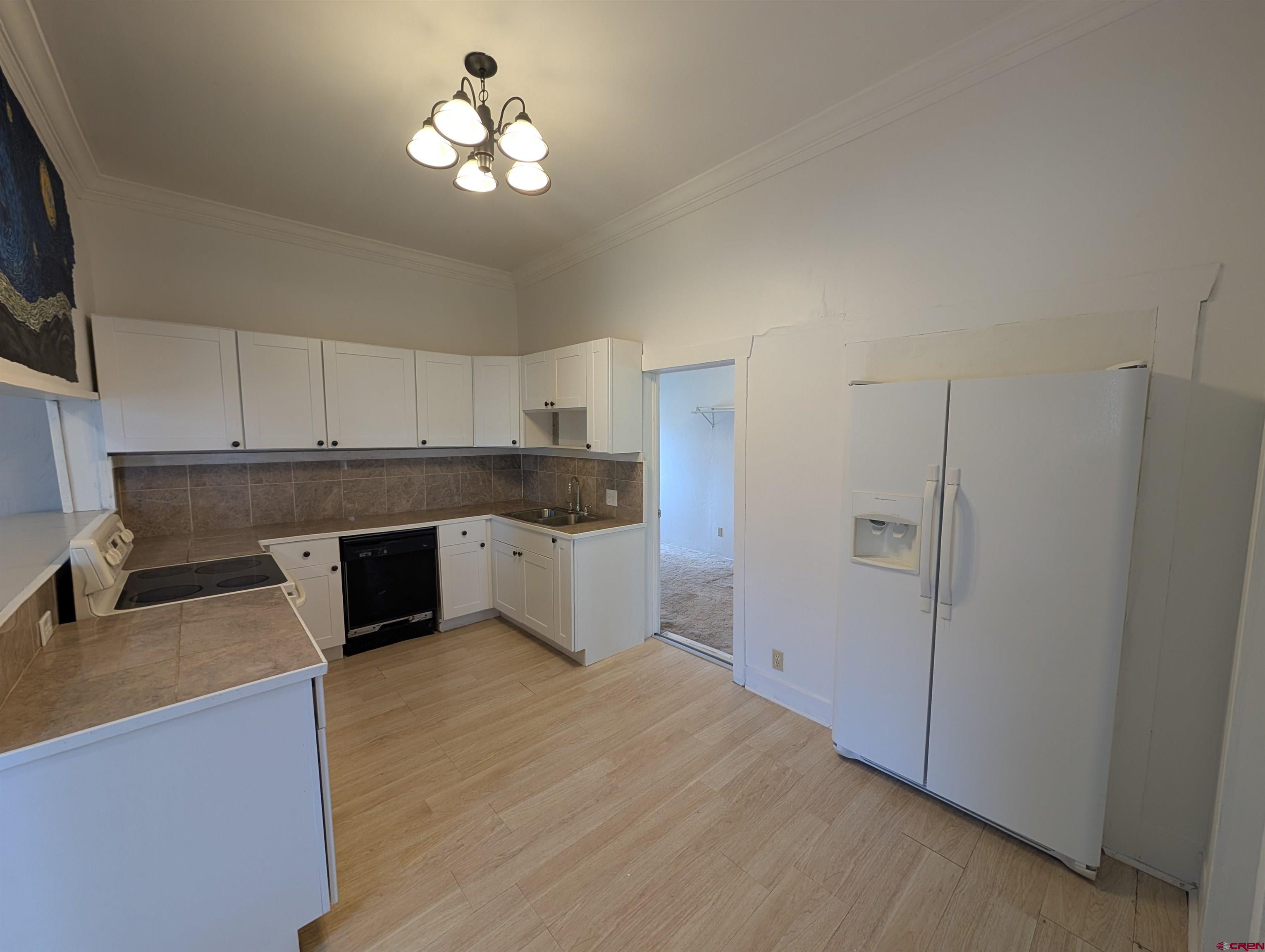 16184 Chipeta Road Montrose, CO 81403 - Photo 5 of 24 a kitchen with stainless steel appliances granite countertop a refrigerator a sink dishwasher and white cabinets with wooden floor