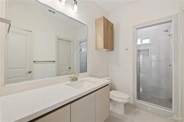 a bathroom with a granite countertop sink a toilet and shower