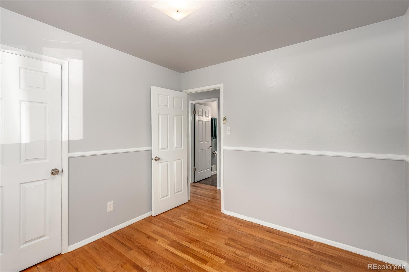 3217 South Stuart Street Denver, CO 80236 - Photo 11 of 30 an empty room with wooden floor and entrance