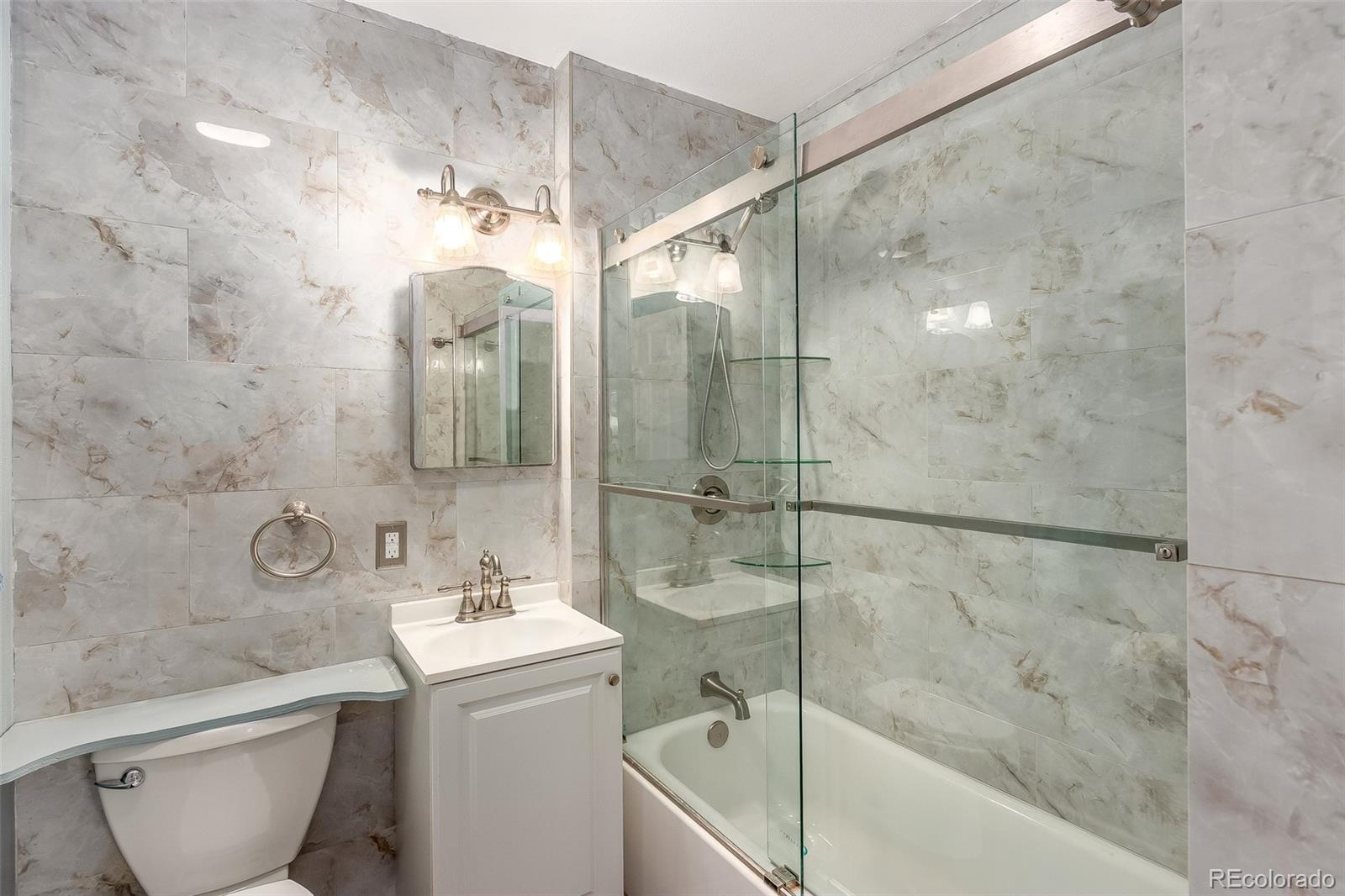 3217 South Stuart Street Denver, CO 80236 - Photo 13 of 30 a bathroom with a bathtub shower sink mirror and toilet