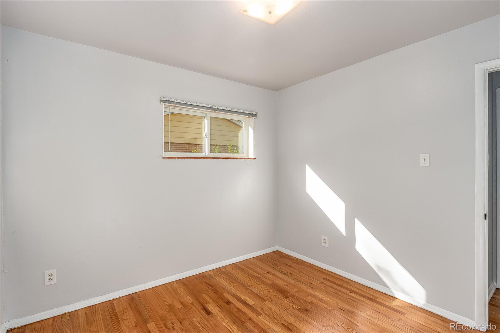 3217 South Stuart Street Denver, CO 80236 - Photo 15 of 30 a view of an empty room with wooden floor and a window